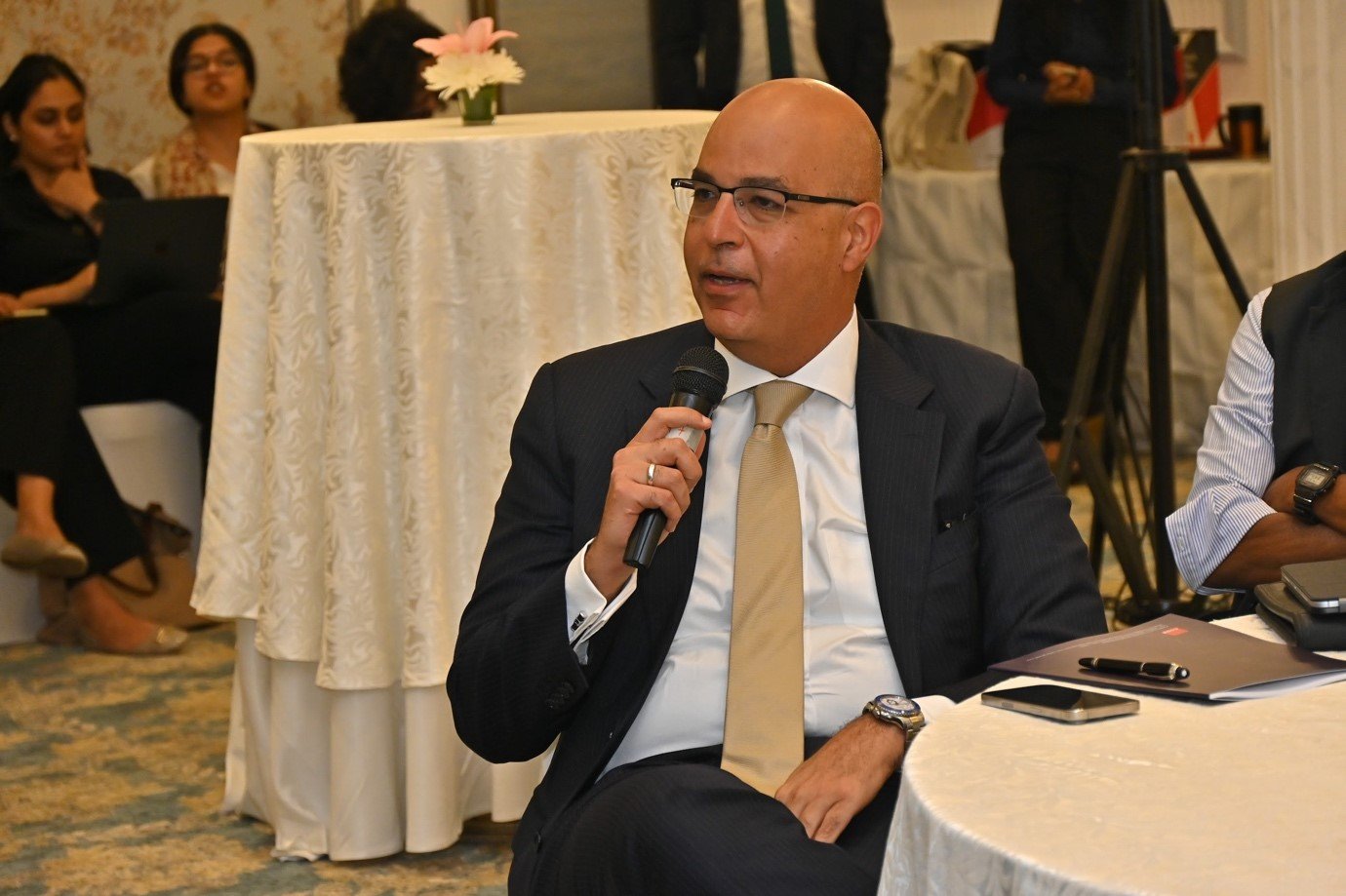 A person in a suit holding a microphone Description automatically generated, Picture